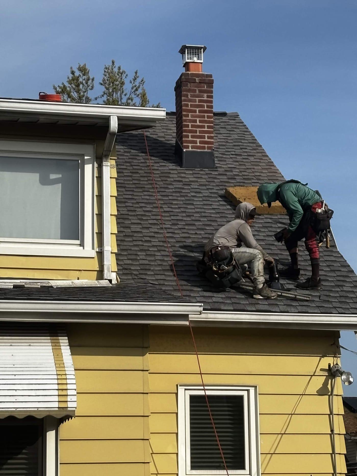 Two Elevate HRG roofers working shingles near the ridge of a New Jersey home